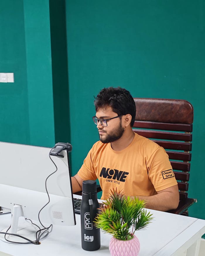 Focused young man in modern office setting working on computer, emphasizing productivity and technology.